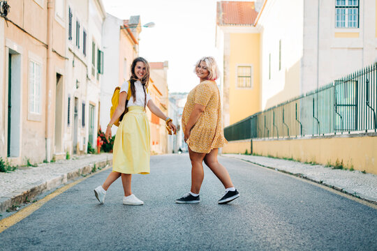 Smiling friends walking together on road in city