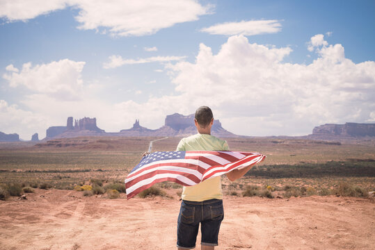 USA, Utah, back view of man with American Flag looking at Monument Valley