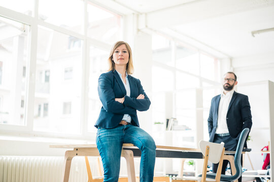 Portrait of confident businesswoman and man in office