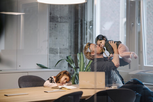 Casual businessman with two daughters working at desk in office