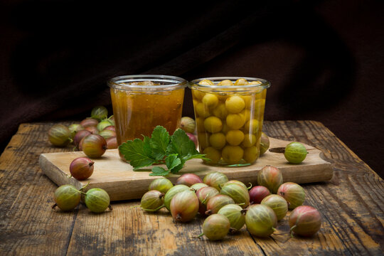 Jar of gooseberry jam, gooseberries and glass of preserved gooseberries on wood
