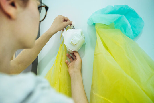 Close-up of doctor taking personal protective equipment from hook in hospital