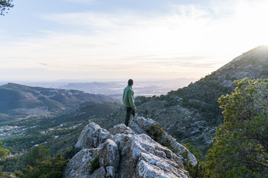 Hiker standing on rocky peak admiring mountain landscape