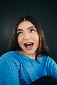 Happy woman expressing surprise looking above with open mouth