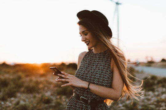 Portrait of young woman looking at cell phone by sunset