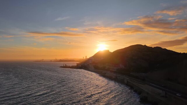 Alicante al atardecer desde el mar con el sol detr&aacute;s del Castillo de Santa Barbara , panor&aacute;mica a&eacute;rea