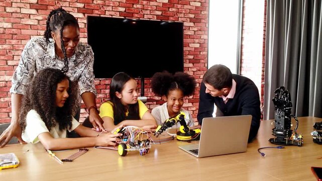 Happy kids celebrate success in a robotics classroom, high-fiving their teacher after completing a STEM coding project. Diverse group with teamwork and innovation spirit in educational tech learning.