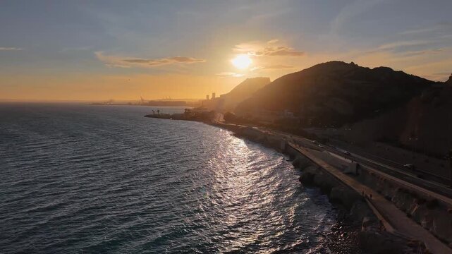 Alicante al atardecer desde el mar con el sol detr&aacute;s del Castillo de Santa Barbara , panor&aacute;mica a&eacute;rea