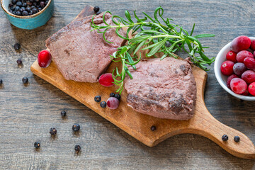 Raw ostrich steaks on wooden board