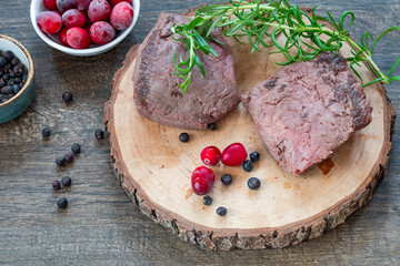 Raw ostrich steaks on wooden board
