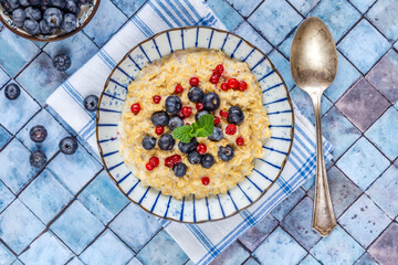 Thick Scottish rolled oats porridge with fresh blueberries and lingonberries