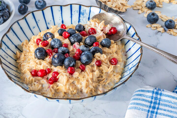 Thick Scottish rolled oats porridge with fresh blueberries and lingonberries