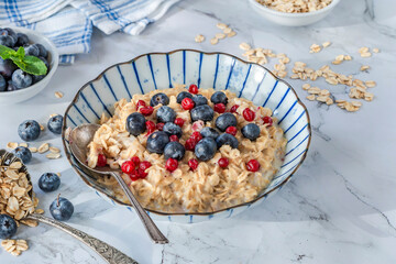 Thick Scottish rolled oats porridge with fresh blueberries and lingonberries