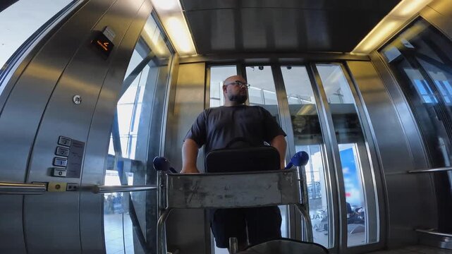 POV man pushes luggage cart out of glass elevator in CPT airport