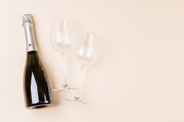 Champagne bottle and glasses on beige background