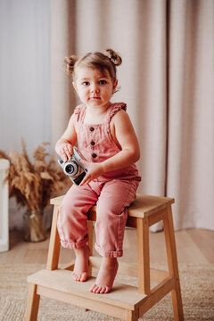 Toddler smiling and playing with toy camera indoors at home