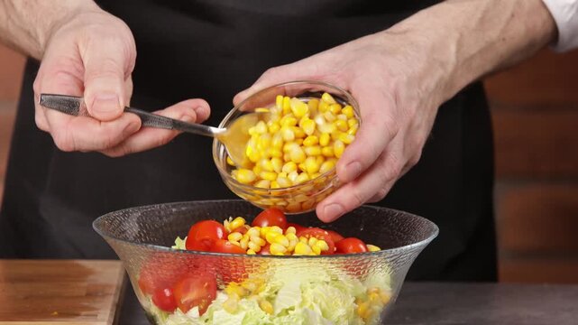 The cook adds cooked canned corn to the bowl and mixes the salad.
