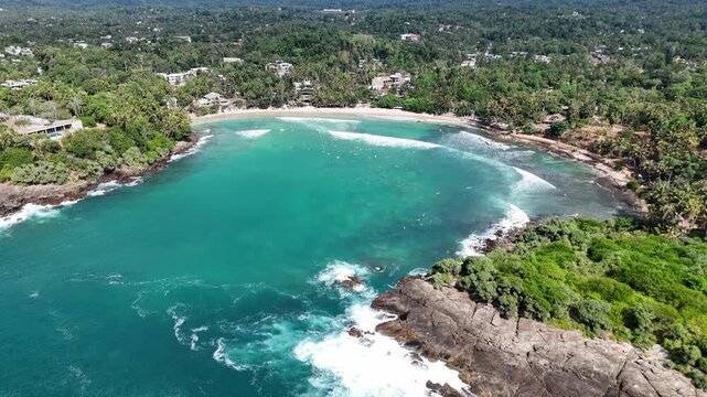 Tropical coastline with surfers in turquoise water, Sri Lanka. Hiriketiya, Dikwella, 4K, 60fps, Drone, Top view