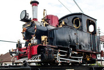 Fototapeta premium Vintage Steam Locomotive Engine Monument Antique Black and Red Train for Historical Transportation and Retro Industrial Heritage Concept Three Quarter View Perspective