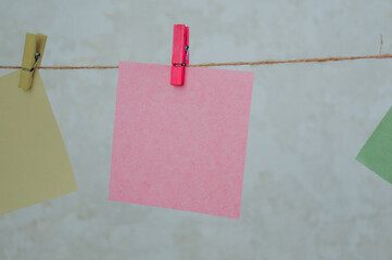 Colorful sticky notes hanging on a string with clothespins. Creative workspace concept, reminders, organization, planning, and minimal decoration idea.