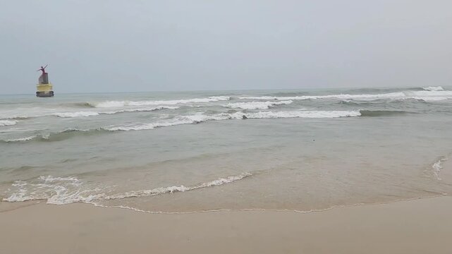 Calm waves washing ashore on a sandy beach on a cloudy day