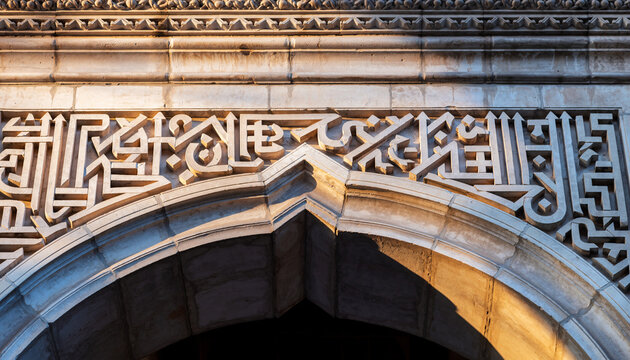 Kufic Script Frieze. Islamic Culture &ndash; Building and Architecture. Architectural frieze where bold, angular Kufic script is carved into pale stone, standing out sharply against the shadow below it.
