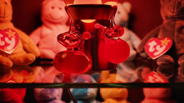 A close-up view of a claw machine with stuffed animals inside illuminated by red light