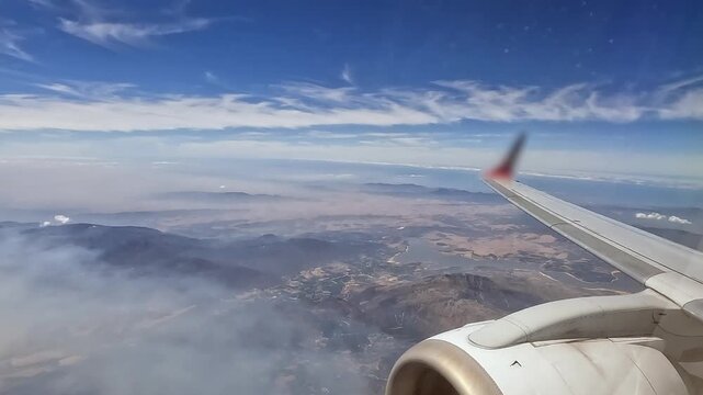 Starboard wing of commercial jet airliner flying over low coastal mtns