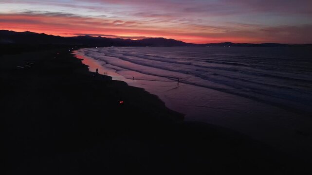 Left aerial view of Eztanza Beach with golden sunset lighting over the shoreline and calm sea in Lingayen, Pangasinan.