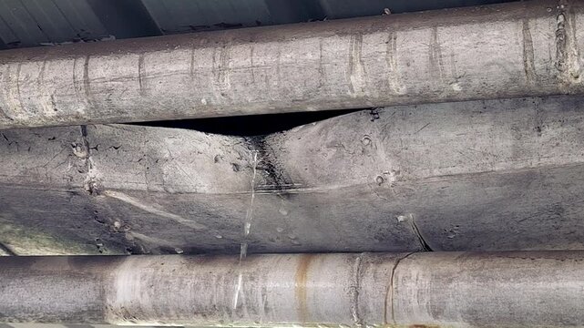 Water leaking from damaged roof slab under urban structure showing infrastructure failure, construction defect, maintenance issue and water wastage problem.