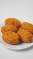 A snack called combro, typical of West Java, Indonesia, made from cassava with oncom chili sauce filling, served on a white plate and placed in a white place (isolated white).