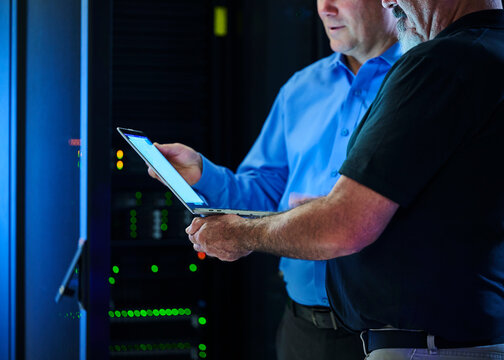 Workers looking at laptop in data center