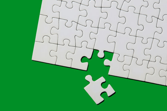Studio shot of white puzzle pieces on green background