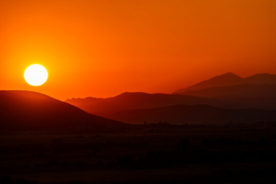 USA, Idaho, Bellevue, Setting sun over hills against orange sky