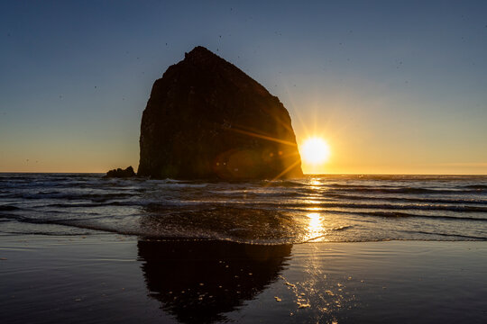 USA, Oregon, Sun setting behind haystack rock on Cannon Beach