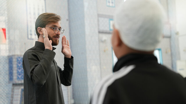Muslim Sheikh teaching kids how to pray in a mosque. Ramadan Quran classes for children. Muslim kids learning Islamic prayer at masjid. Taraweeh prayer and Ramadan atmosphere.