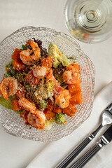 Warm shrimp salad with roasted vegetables fresh herbs and cheese served on elegant glass plate