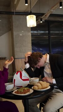 Vertical screen tired boyfriend dozes off during valentines date as he leans forward at the cafe table showing exhaustion and awkward silence while the couple tries to keep the moment light
