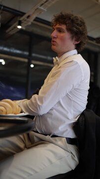 Vertical screen a nervous young man on valentines day struggles with tension during a cafe date taking off his jacket in frustration as the mood shifts and something clearly goes wrong