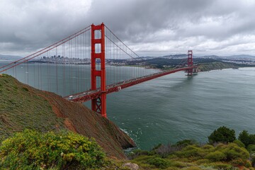 Fototapeta premium A scenic view of an iconic orange suspension bridge spanning a waterway under an overcast sky