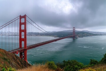 Fototapeta premium Long-span suspension bridge spanning open water under a dramatic, cloudy sky