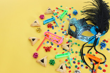 Purim celebration concept (jewish carnival holiday) over yellow background
