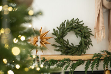 Cozy Christmas decor on mantel: evergreen wreath, gold starburst, warm scarf, soft lights.