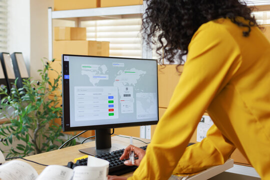 Small Business Fulfillment With Female Entrepreneur using computer to managing order, monitoring shipment detail, online tracking order looking at dashboard on screen while working in warehouse office