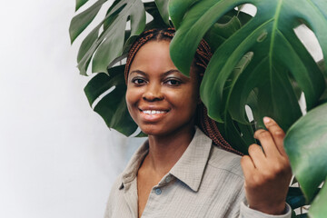 A young, cheerful African American woman smiles charmingly surrounded by lush tropical vegetation