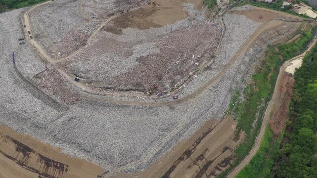 High aerial view showing a massive garbage dump with piles of plastic waste and trash, highlighting the severe environmental pollution crisis and problems with waste management in bali