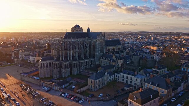 Wide aerial establishing shot of Saint Julien Cathedral dominating cityscape of Le Mans at sunset, France. Aerial drone forward