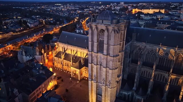 Aerial orbit around glowing Cath&eacute;drale Saint-Julien after dark, old town of Le Mans, France