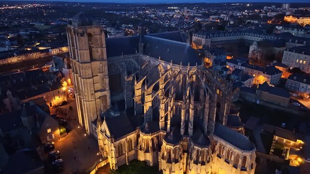 Cathedral of Saint-Julien at night, revealing its architectural splendor against the dark city, France. Aerial drone backward