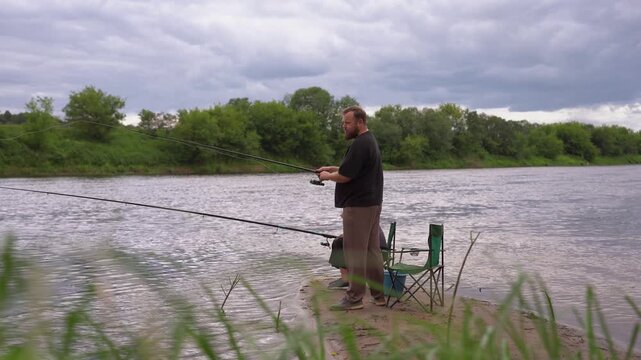 Man and girl enjoying quiet fishing on the riverbank, holding fishing rods and waiting for a catch on a cloudy day, demonstrating a relaxing hobby in the fresh air and male communication